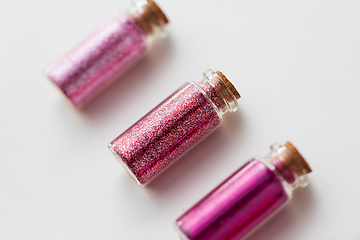 Image showing red glitters in bottles over white background