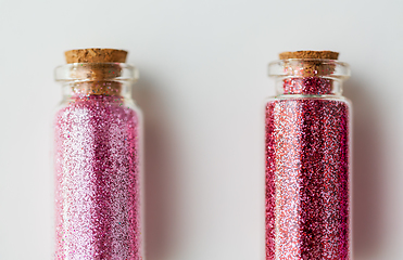 Image showing red glitters in bottles over white background