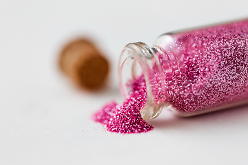 Image showing pink glitters poured from small glass bottle