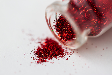 Image showing red glitters poured from small glass bottle