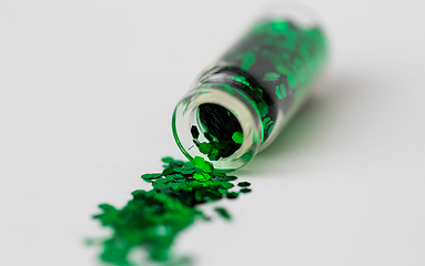 Image showing green glitters poured from small glass bottle