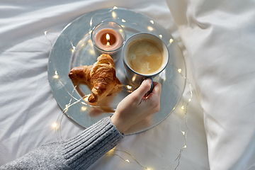 Image showing hand of woman drinking coffee with croissant