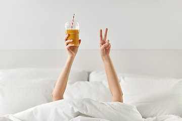 Image showing hands of woman lying in bed with cup of juice