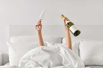 Image showing hands of woman lying in bed with champagne