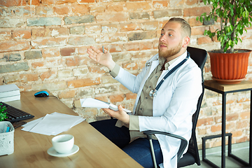 Image showing Caucasian doctor consulting for patient, explaining recipe for drug, working in cabinet