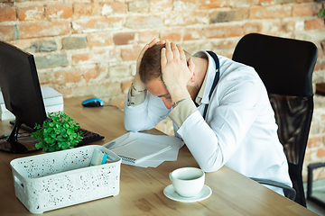 Image showing Caucasian doctor resting after consulting for patient, working in cabinet