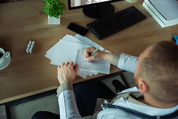 Image showing Caucasian doctor has online conference with colleague, consulting, working in cabinet