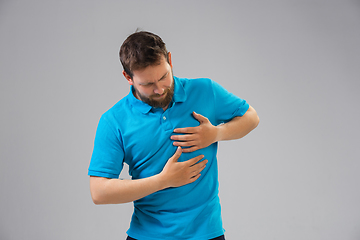 Image showing Young man suffers from pain, feels sick, ill and weakness isolted on studio background