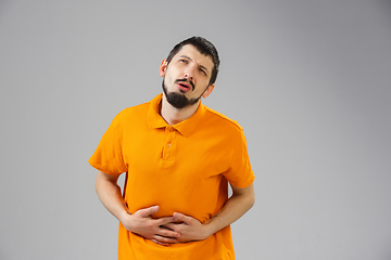 Image showing Young man suffers from pain, feels sick, ill and weakness isolted on studio background