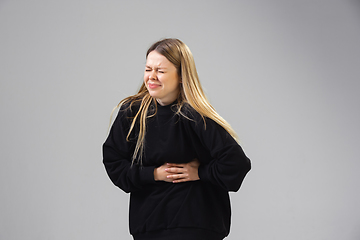 Image showing Young woman suffers from pain, feels sick, ill and weakness isolted on studio background