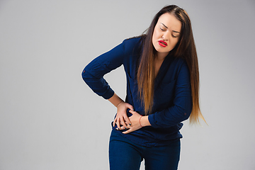 Image showing Young woman suffers from pain, feels sick, ill and weakness isolted on studio background