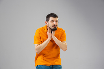 Image showing Young man suffers from pain, feels sick, ill and weakness isolted on studio background