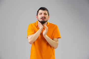 Image showing Young man suffers from pain, feels sick, ill and weakness isolted on studio background