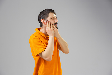 Image showing Young man suffers from pain, feels sick, ill and weakness isolted on studio background