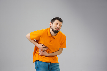 Image showing Young man suffers from pain, feels sick, ill and weakness isolted on studio background