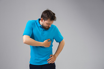 Image showing Young man suffers from pain, feels sick, ill and weakness isolted on studio background