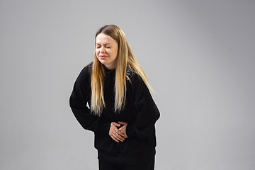 Image showing Young woman suffers from pain, feels sick, ill and weakness isolted on studio background