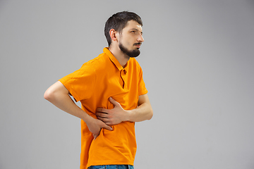 Image showing Young man suffers from pain, feels sick, ill and weakness isolted on studio background