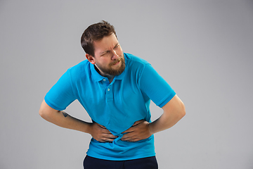 Image showing Young man suffers from pain, feels sick, ill and weakness isolted on studio background