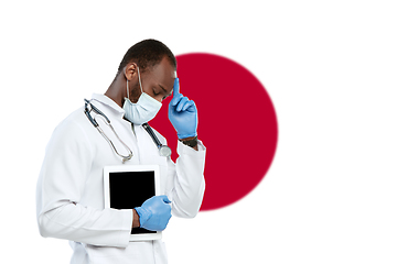 Image showing Young doctor with stethoscope and face mask praying for God with Japan national flag on background