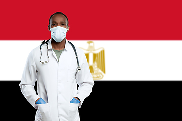 Image showing Young doctor with stethoscope and face mask praying for God with Egypt national flag on background