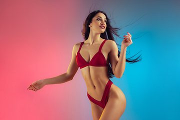 Image showing Fashion portrait of young fit and sportive woman in stylish red luxury swimwear on gradient background. Perfect body ready for summertime.