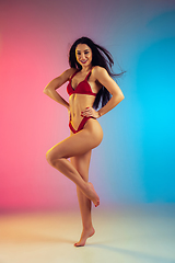 Image showing Fashion portrait of young fit and sportive woman in stylish red luxury swimwear on gradient background. Perfect body ready for summertime.