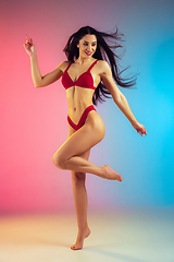 Image showing Fashion portrait of young fit and sportive woman in stylish red luxury swimwear on gradient background. Perfect body ready for summertime.