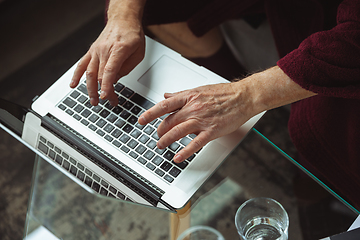 Image showing Mature senior older man during quarantine, realizing how important stay at home during virus outbreak, close up of hands typing text