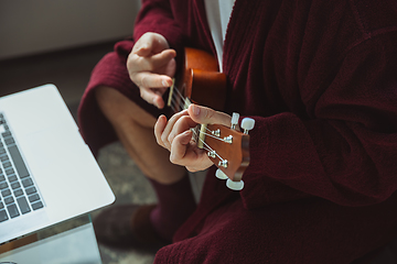 Image showing Mature senior older man during quarantine, virus outbreak, giving concert of taking online lessons of guitar playing, close up of hands