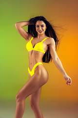 Image showing Fashion portrait of young fit and sportive woman in stylish yellow luxury swimwear on gradient background. Perfect body ready for summertime.