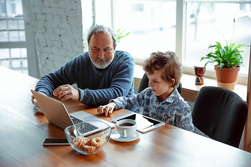 Image showing Grandfather and his grandson spending time insulated at home, stadying, watching cinema, shopping together