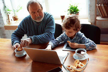 Image showing Grandfather and his grandson spending time insulated at home, stadying, watching cinema, shopping together