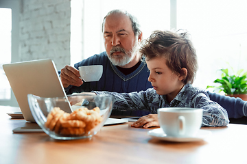 Image showing Grandfather and his grandson spending time insulated at home, stadying, watching cinema, shopping together