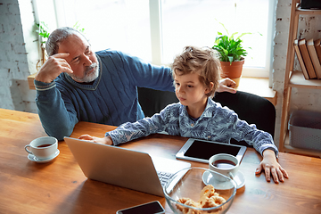 Image showing Grandfather and his grandson spending time insulated at home, stadying, watching cinema, shopping together