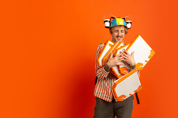 Image showing Contacless delivery service during quarantine. Man delivers food and shopping bags during insulation. Emotions of deliveryman isolated on orange background.