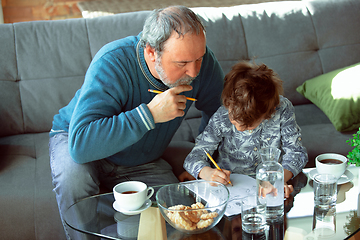 Image showing Grandfather and his grandson spending time insulated at home, stadying, writing, drawing or playing together