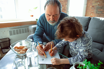 Image showing Grandfather and his grandson spending time insulated at home, stadying, writing, drawing or playing together