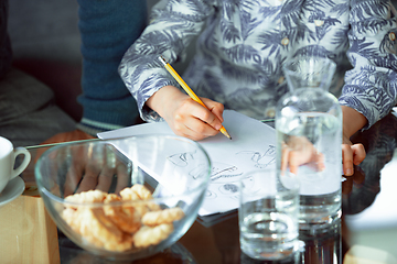 Image showing Grandfather and his grandson spending time insulated at home, stadying, writing, drawing or playing together, close up of hands