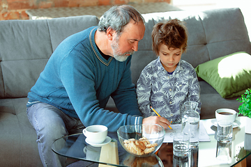 Image showing Grandfather and his grandson spending time insulated at home, stadying, writing, drawing or playing together