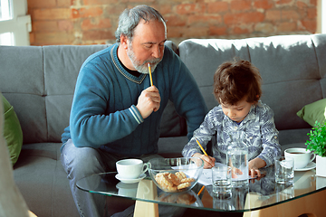 Image showing Grandfather and his grandson spending time insulated at home, stadying, writing, drawing or playing together