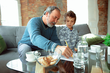 Image showing Grandfather and his grandson spending time insulated at home, stadying, writing, drawing or playing together