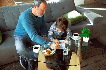 Image showing Grandfather and his grandson spending time insulated at home, stadying, writing, drawing or playing together