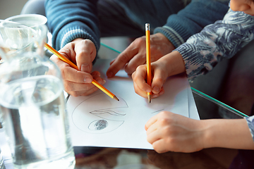 Image showing Grandfather and his grandson spending time insulated at home, stadying, writing, drawing or playing together, close up of hands