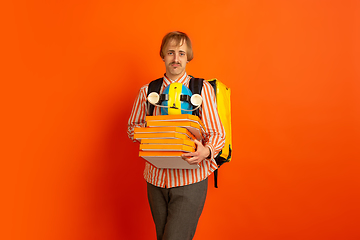 Image showing Contacless delivery service during quarantine. Man delivers food and shopping bags during insulation. Emotions of deliveryman isolated on orange background.