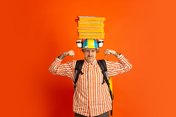 Image showing Contacless delivery service during quarantine. Man delivers food and shopping bags during insulation. Emotions of deliveryman isolated on orange background.