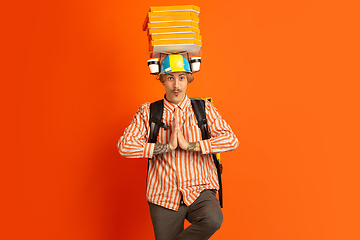 Image showing Contacless delivery service during quarantine. Man delivers food and shopping bags during insulation. Emotions of deliveryman isolated on orange background.