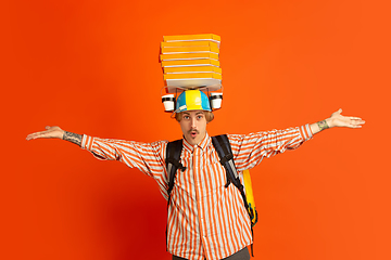 Image showing Contacless delivery service during quarantine. Man delivers food and shopping bags during insulation. Emotions of deliveryman isolated on orange background.