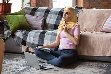 Image showing A pretty young muslim woman at home during quarantine and self-insulation, using laptop, listen to music, watching cinema, serials, shopping, studying