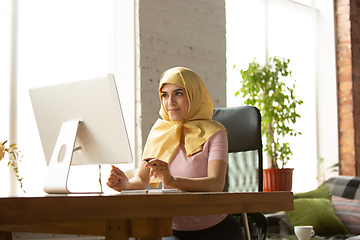 Image showing A pretty young muslim woman at home during quarantine and self-insulation, remote working, shopping, studying, watching cinema